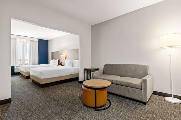 A hotel room with a bed, a sofa, a round table, and a lamp. - Spark by Hilton Catoosa Tulsa (Catoosa)