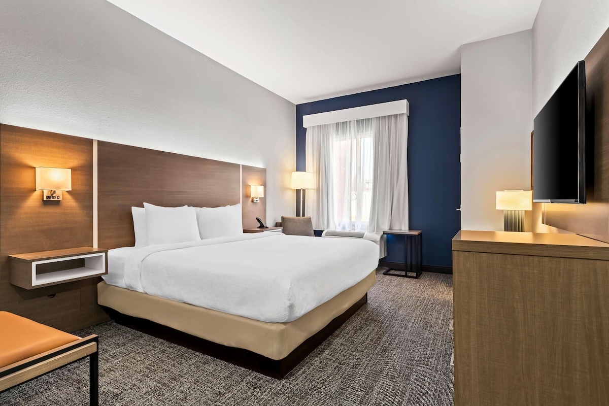 Une chambre d’hôtel avec un grand lit, des tables de chevet, un bureau et un téléviseur.