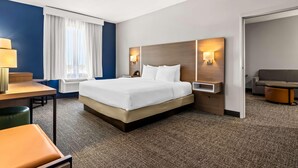 Una habitación de hotel con cama, escritorio, silla, sofá y lámpara.