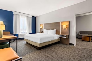 Une chambre d’hôtel avec un lit, un bureau, une chaise, un canapé et une lampe.