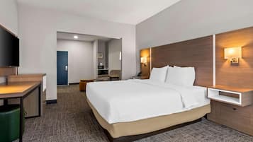 Ein Hotelzimmer mit einem Bett, einem Schreibtisch, einem Stuhl, einem Fernseher und einem Nachttisch mit Lampe.