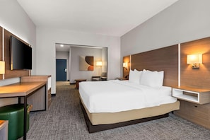 Una habitación de hotel con cama, escritorio, televisor y espejo.