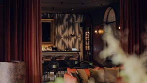 A bar area with a laptop, bar stools, and a patterned wall. - Flaner Hotel, WorldHotels Crafted (Warsaw)
