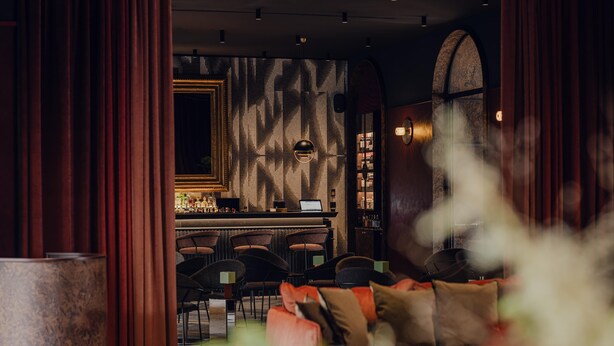 Un espace bar équipé d’un ordinateur portable, de tabourets de bar et d’un mur décoré de motifs.