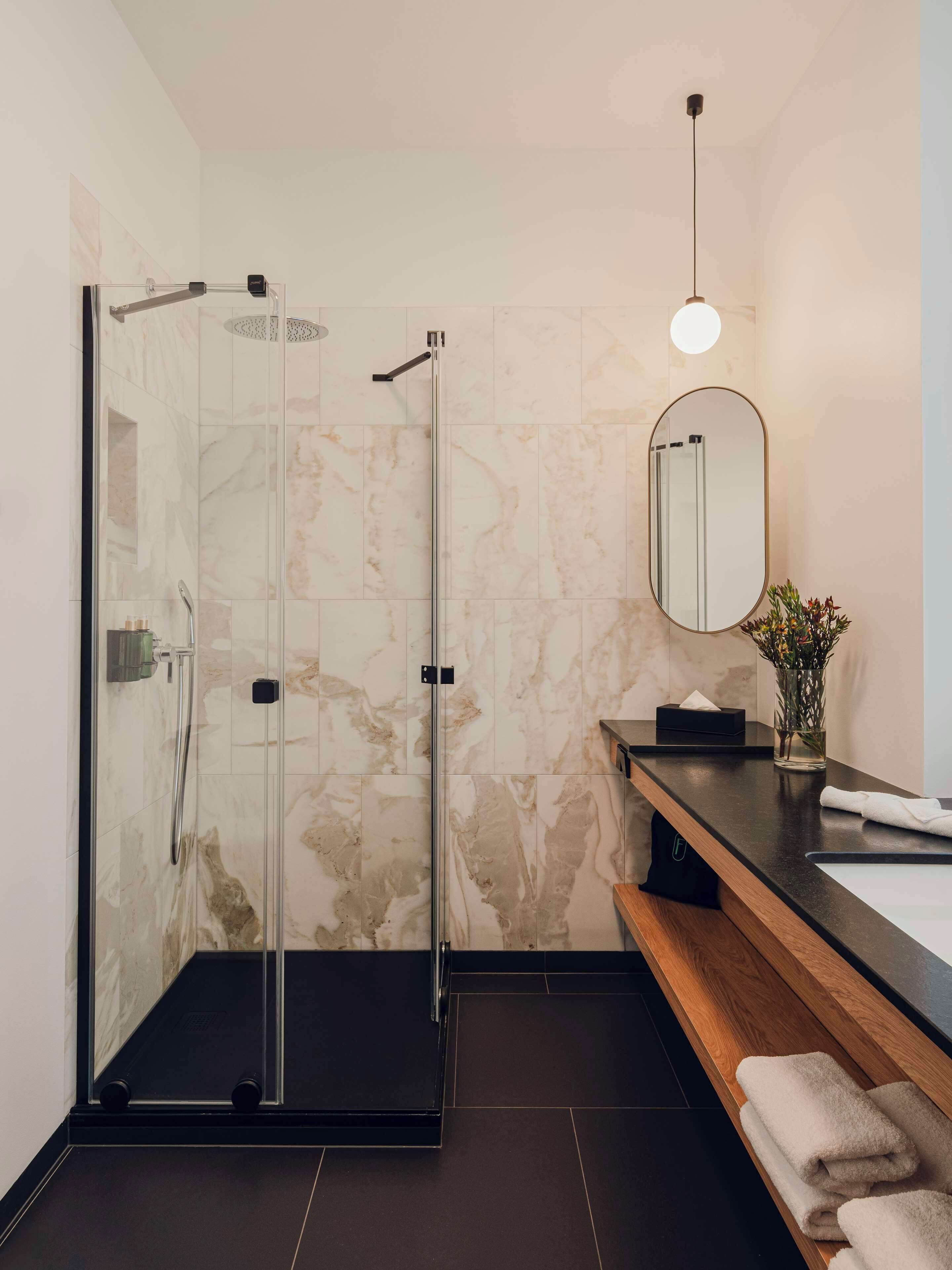 Un baño moderno con cabina de ducha de vidrio, tocador de madera y espejo.