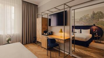 A hotel room with a bed, a desk with a chair, a TV, and a large mirror.