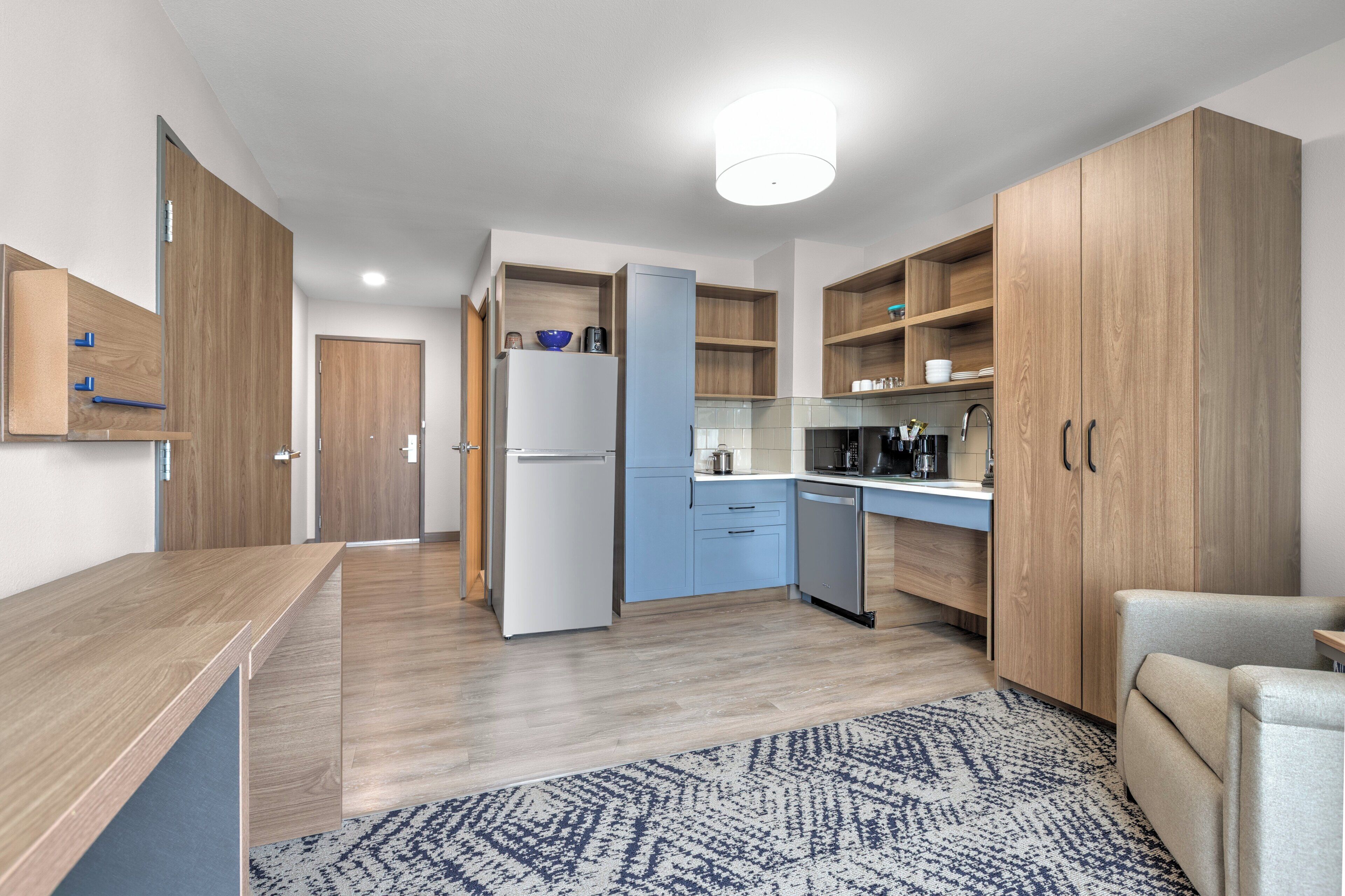 A modern kitchen with wooden cabinets, a refrigerator, a sink, and a countertop.
