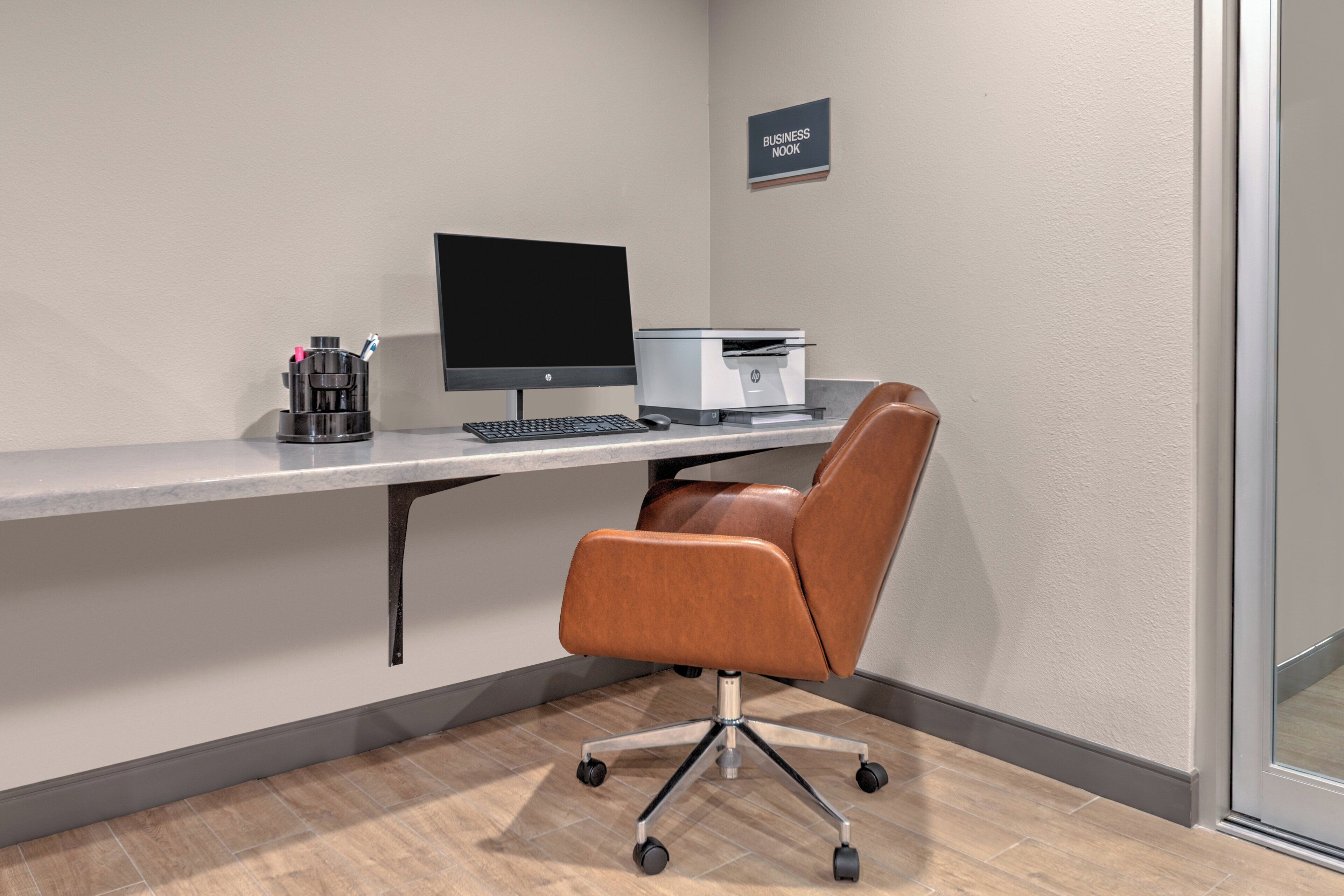 A business office with a desk, computer, printer, and leather chair.