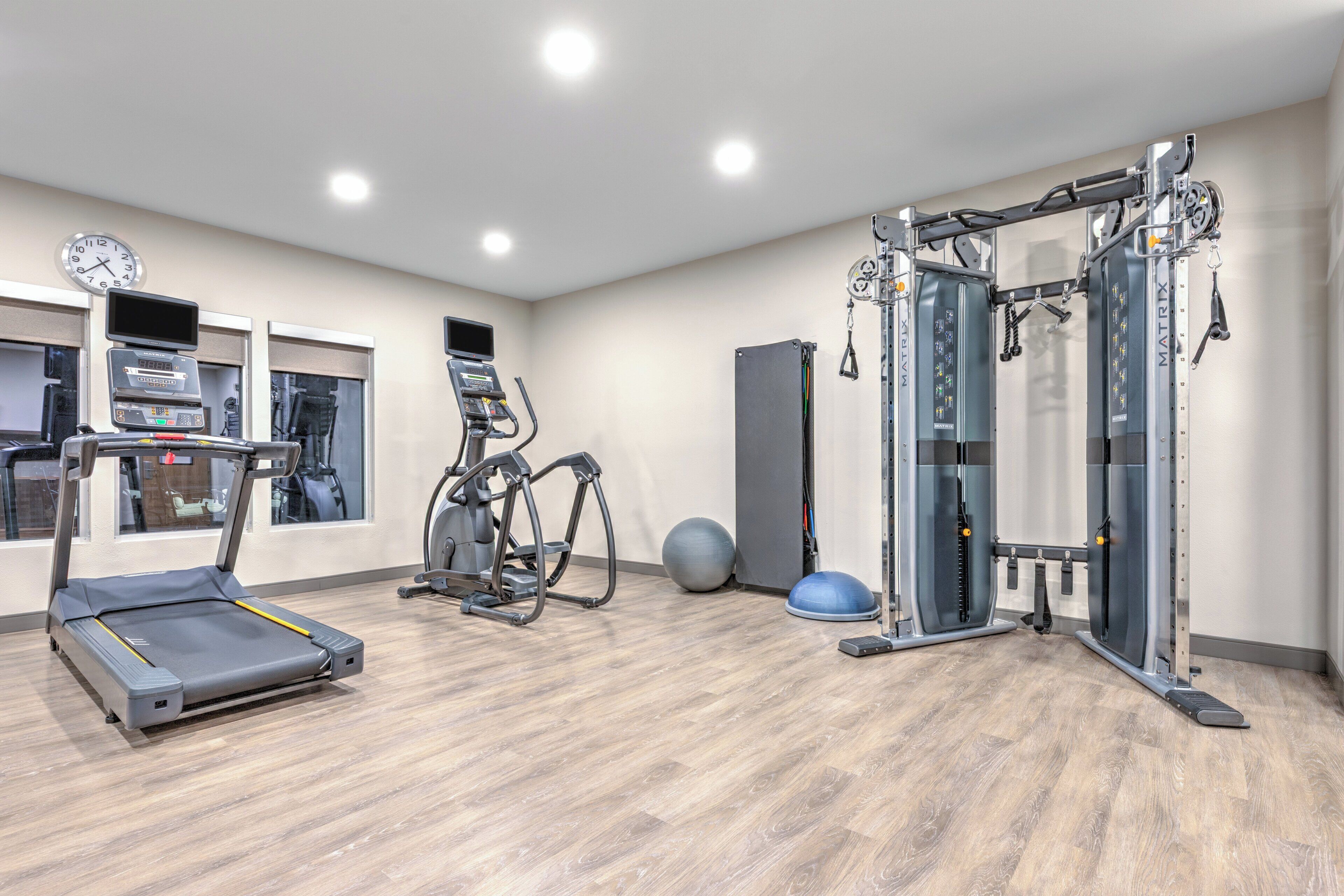 A gym with a treadmill, elliptical, and weight machines.