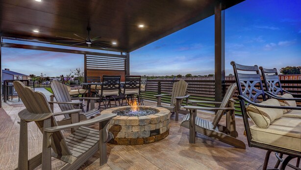 An outdoor patio with a stone fire pit, wooden chairs, and tables. - Candlewood Suites Navasota by IHG (Navasota)