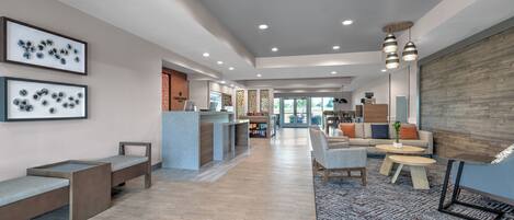 A spacious lobby with a reception desk, seating areas, and a patterned rug.