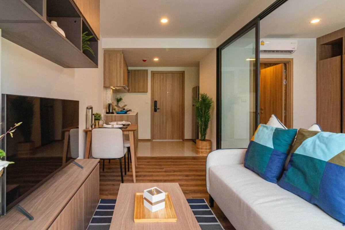 Una sala de estar moderna con un sofá, una mesa de centro y un televisor. Hay un comedor con una mesa y sillas.