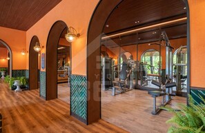 Une salle de sport avec un plancher en bois, des murs recouverts de miroirs et du matériel d’exercice.