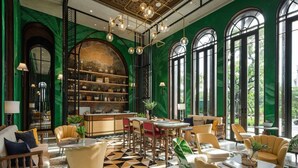 Eine geräumige Lobby mit Schachbrettmuster-Boden, grünen Wänden und großen Rundbogenfenstern.