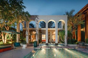 Un bâtiment moderne doté d’une cour intérieure, de colonnes en arc de cercle et d’une piscine.