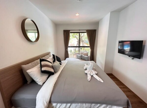Une chambre d’hôtel avec un lit, une télévision, une fenêtre avec des rideaux et un miroir au mur.