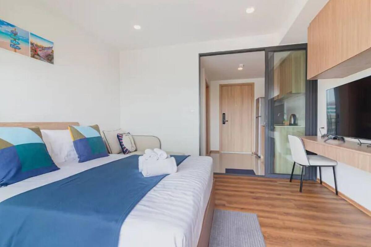 Habitación de hotel moderna con una cama grande, un escritorio y una televisión.