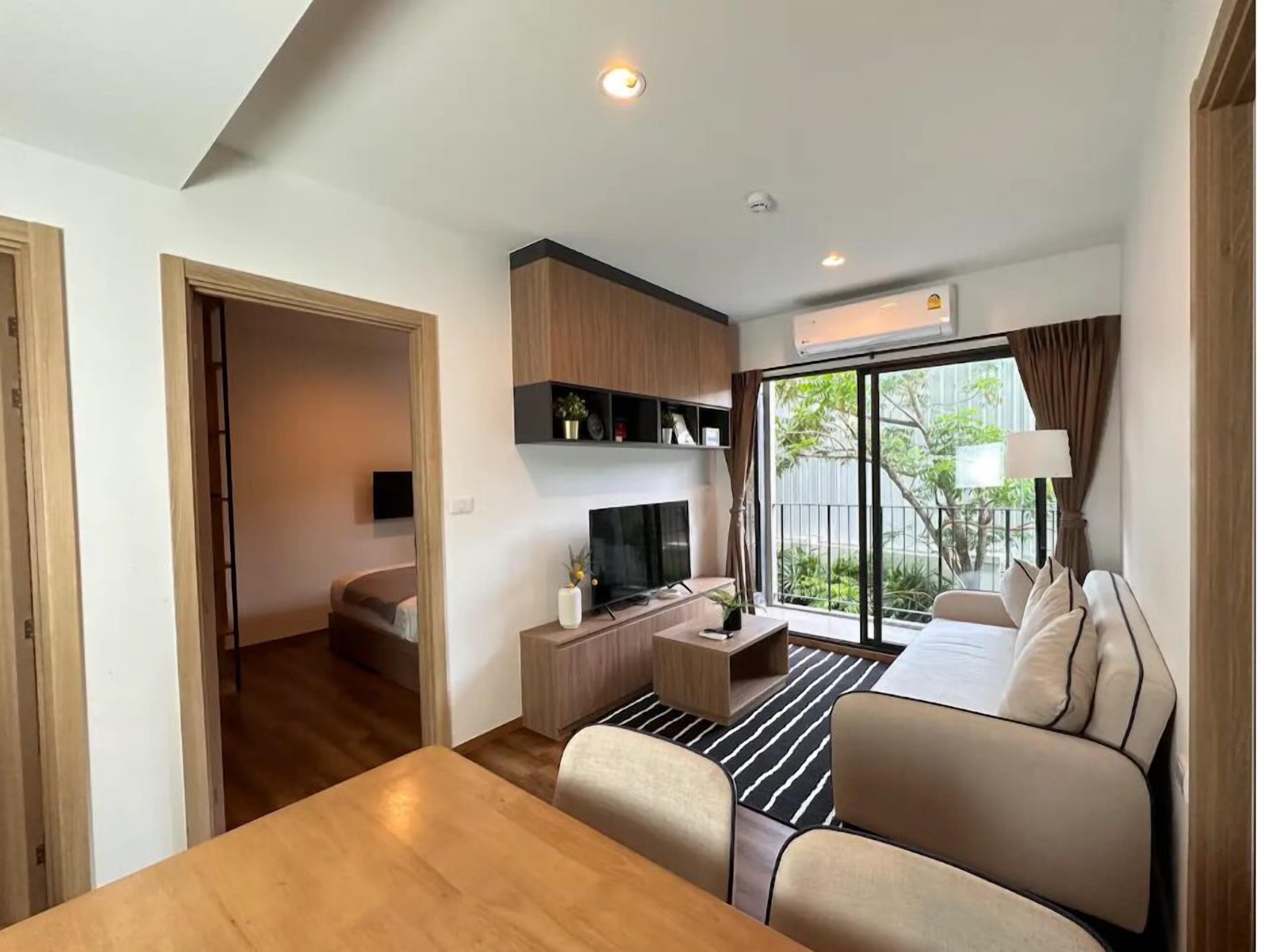 A modern living room with a sofa, TV, and a dining area.