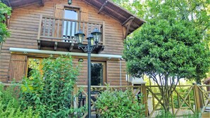 Una cabaña de madera con balcón, porche y jardín.