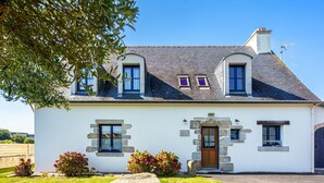 A two-story house with a stone facade, a wooden door, and a stone bench in the front yard. - La mouette bleue by Interhome (Loctudy)