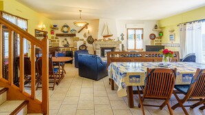 A cozy dining area with a wooden table and chairs, a blue sofa, and a fireplace. - La mouette bleue by Interhome (Loctudy)