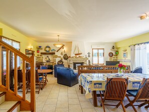 Ein gemütlicher Essbereich mit Holztisch und -stühlen, einem blauen Sofa und einem Kamin.