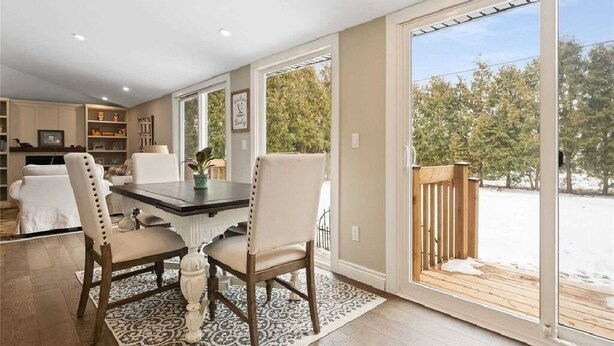 A dining area with a table and chairs, a rug, and a view of a snowy outdoor deck. - Perfection Near the River (Niagara Falls)
