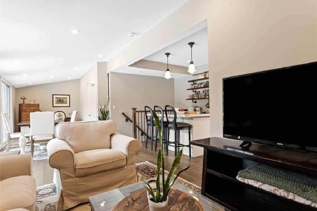 Ein modernes Wohnzimmer mit Sofa, Fernseher und Essbereich.