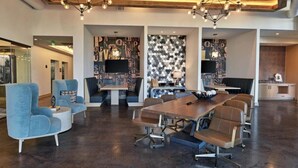 A modern conference room with a large table, blue and brown chairs, and a patterned wall. - Deep Ellum Lux apartment with endless amenities! (Dallas)
