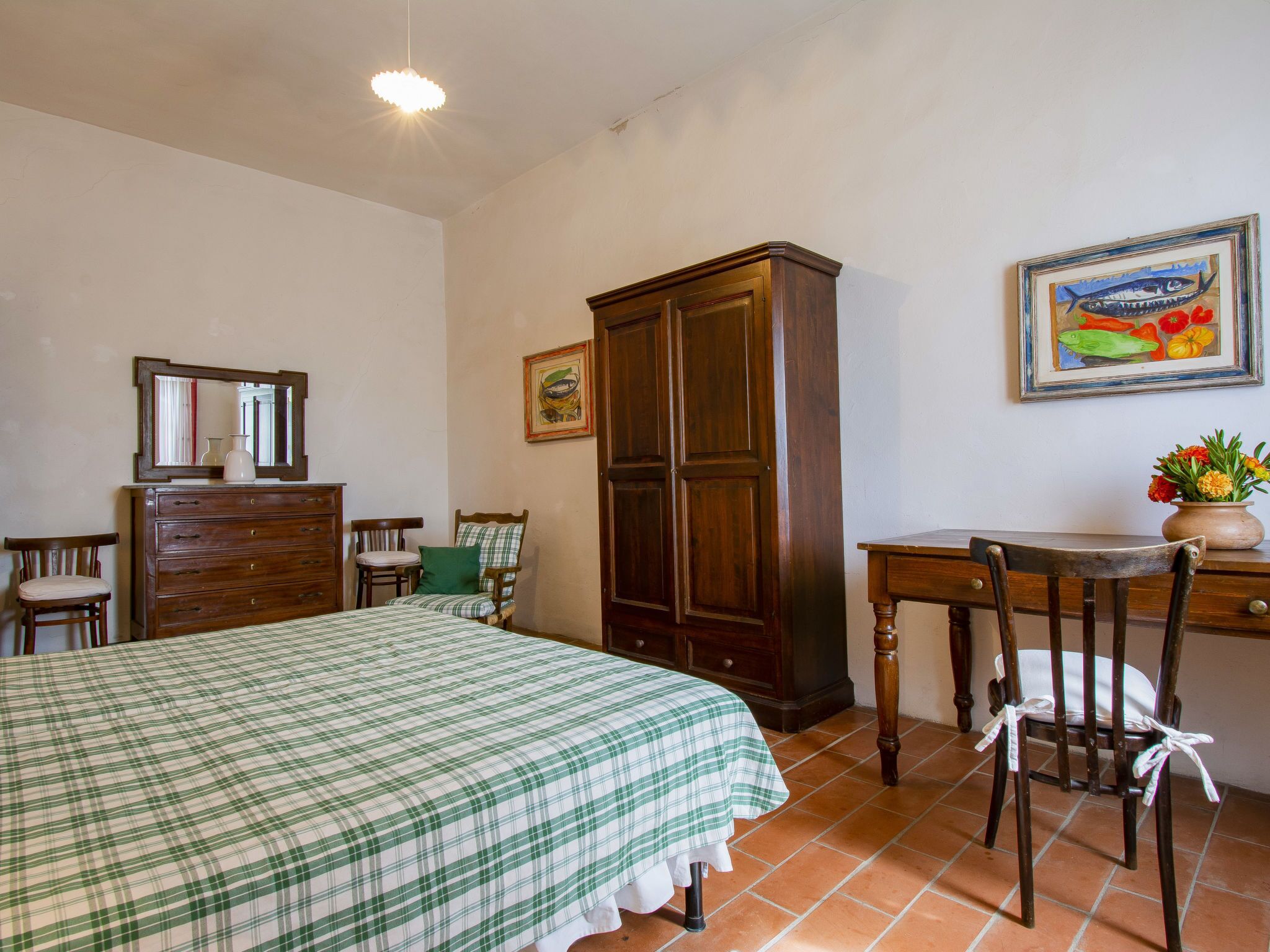 A bedroom with a bed, dresser, chair, desk, and a cabinet.