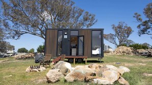Een moderne, compacte accommodatie met een schuifdeur, een klein terras en uitzicht op het omliggende landschap.