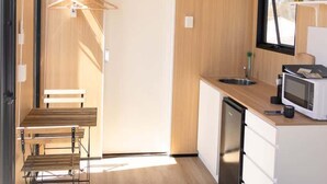 Een compacte, moderne keuken met houten wanden, een bankje, een spoelbak en een magnetron.