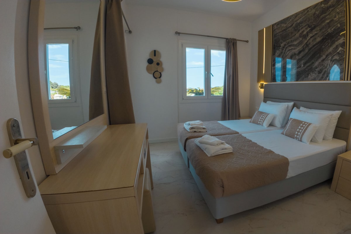 Habitación de hotel con cama, escritorio, cómoda y un espejo grande.