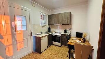 A compact kitchen with a stove, sink, and cabinets.