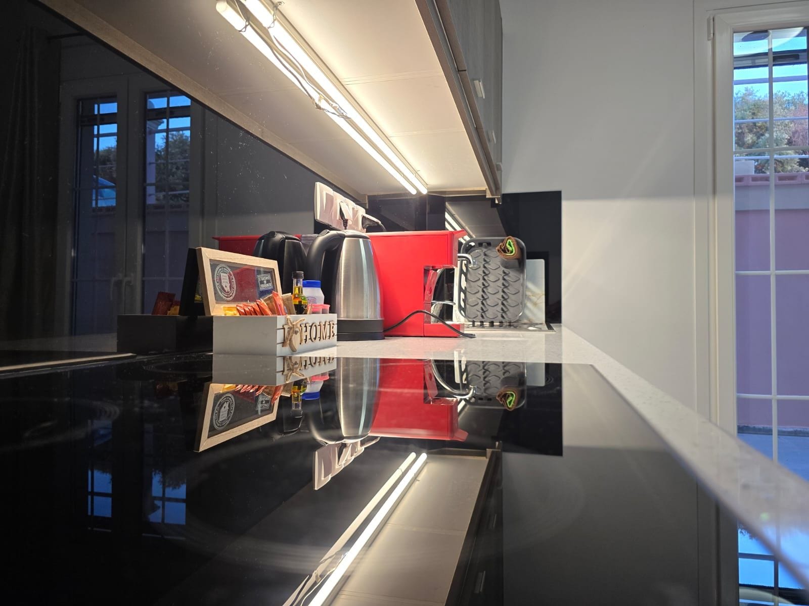 Eine moderne Küche mit glänzendem Arbeitsplatz, einem roten Gerät und einer Kaffeemaschine.