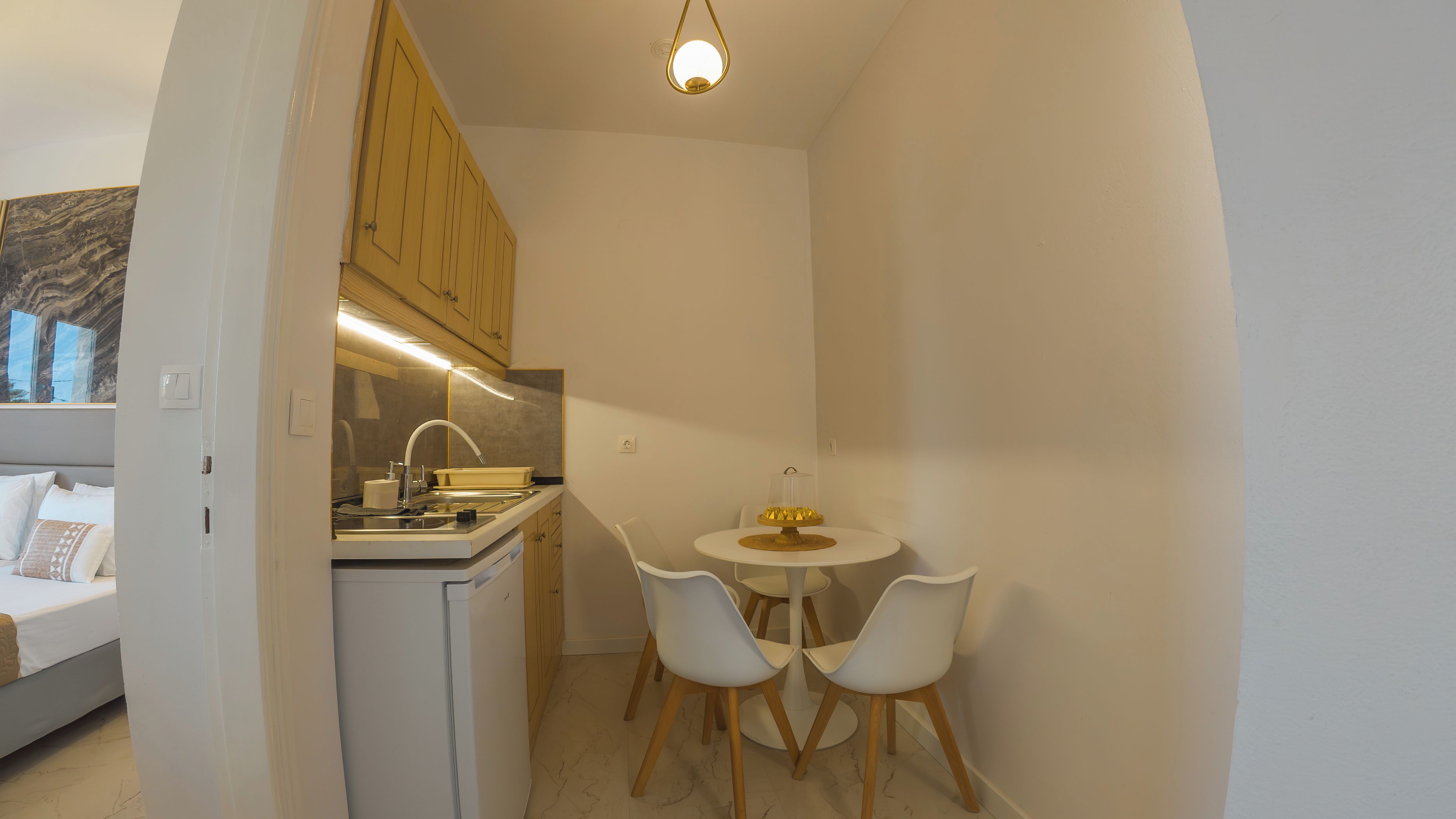 A compact kitchen with a sink, stove, and wooden cabinets. There is a small dining area with two chairs and a table.