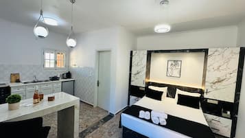 Ein modernes Schlafzimmer mit einem großen Bett, einem Nachttisch und einem Schreibtisch mit Stuhl. Ein Fenster bietet einen Ausblick nach draußen.