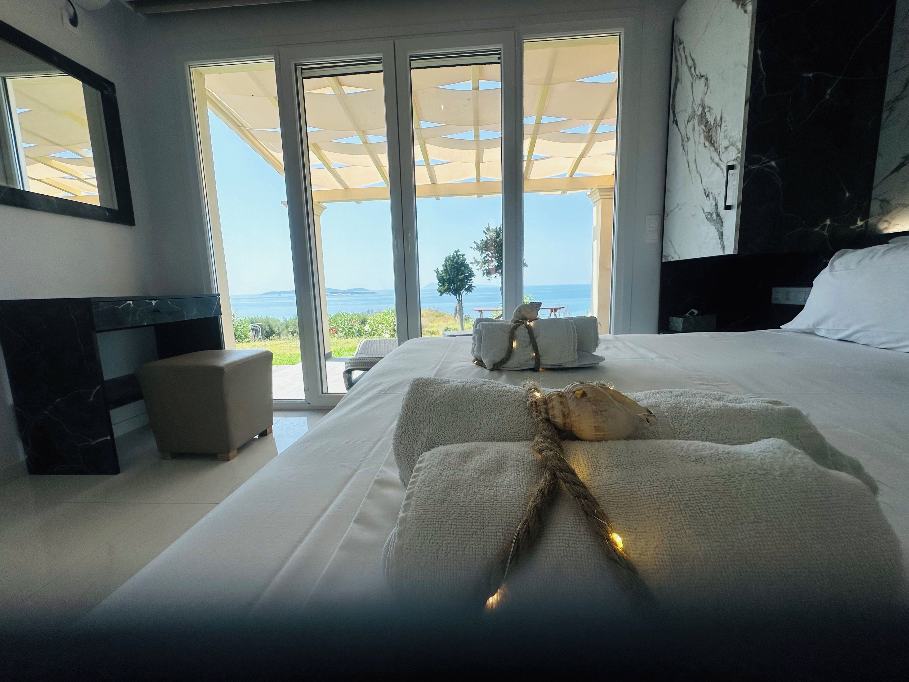 Ein Schlafzimmer mit einem großen Bett, einem Nachttisch und Meerblick durch große Fenster.