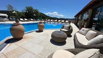 A poolside area with wicker furniture, large vases, and a clear view of the surrounding landscape.