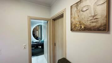 Un corridoio con uno specchio, un lavandino e un quadro appeso al muro.