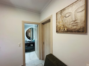 A hallway with a mirror, a sink, and a framed artwork on the wall. - Nikos Apartments Corfu (Corfu)