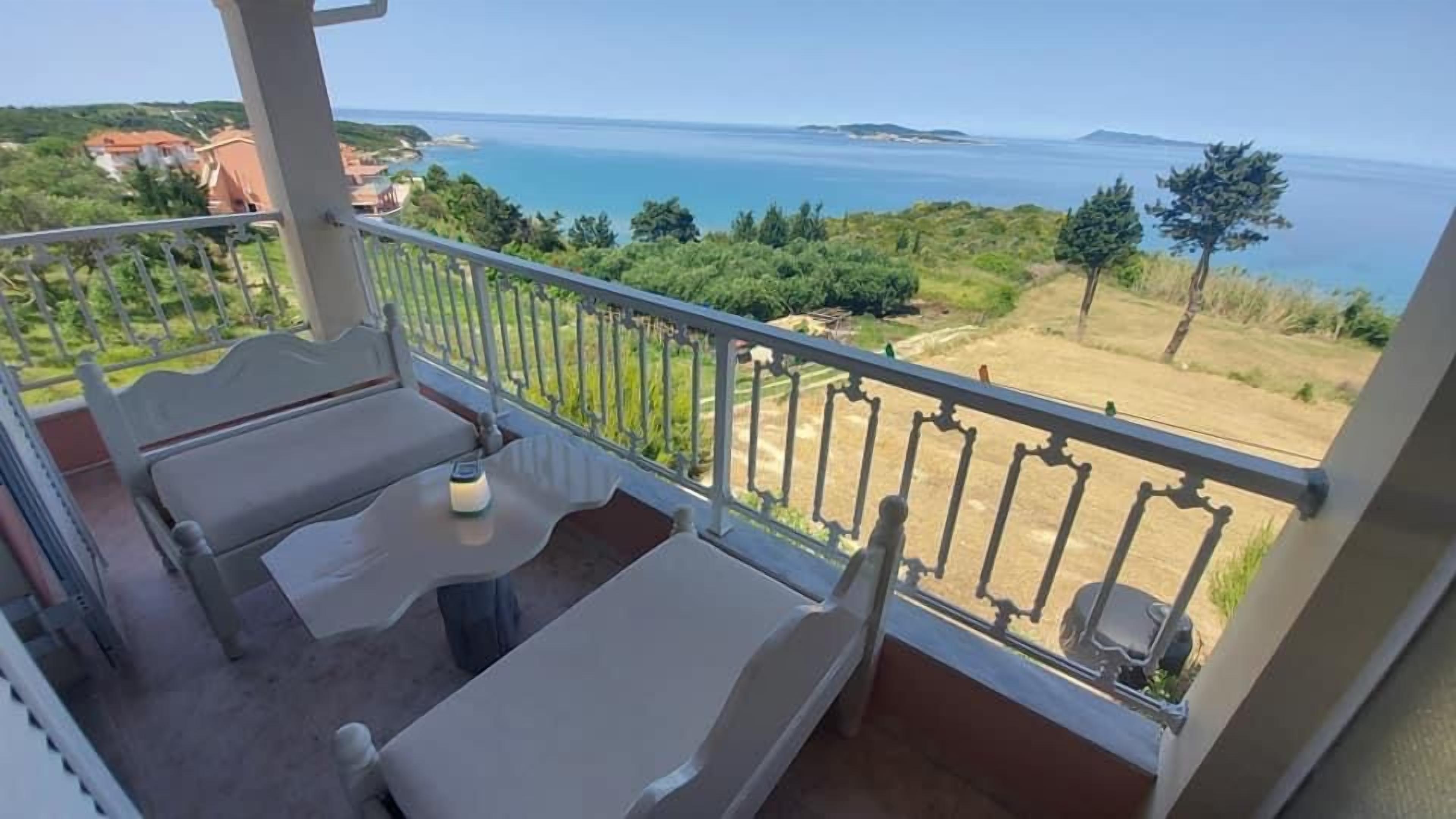 Un balcon avec vue sur la mer et la verdure.