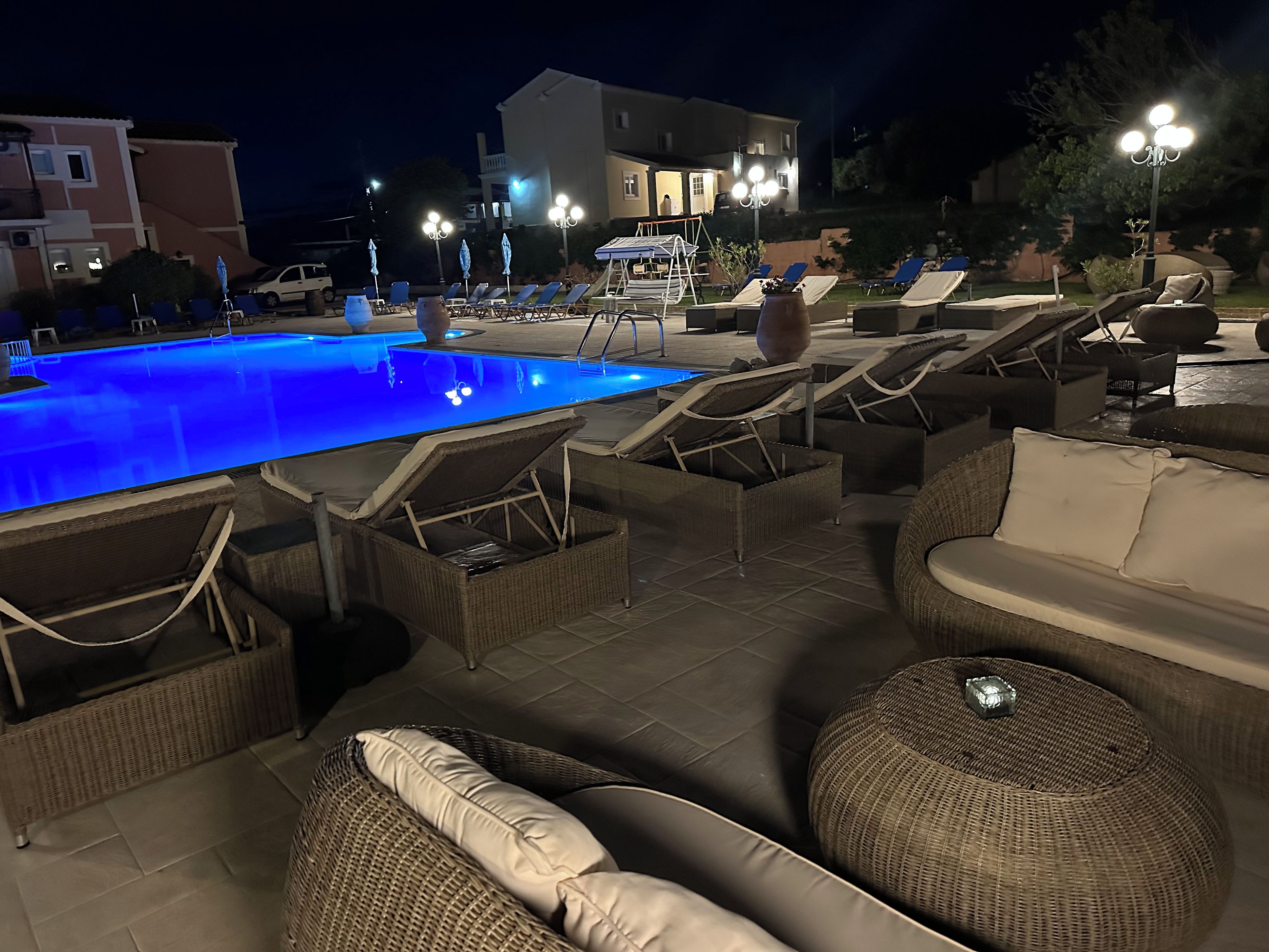 Un espace aménagé au bord de la piscine, avec des chaises longues et une piscine éclairée la nuit.