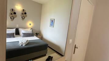 Una habitación de hotel con un espejo grande, una cama con almohadas, una mesita de noche con una bandeja y un ventilador de techo.