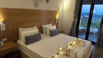 Habitación de hotel con una cama grande, cabecera de madera y vista al mar desde un balcón.