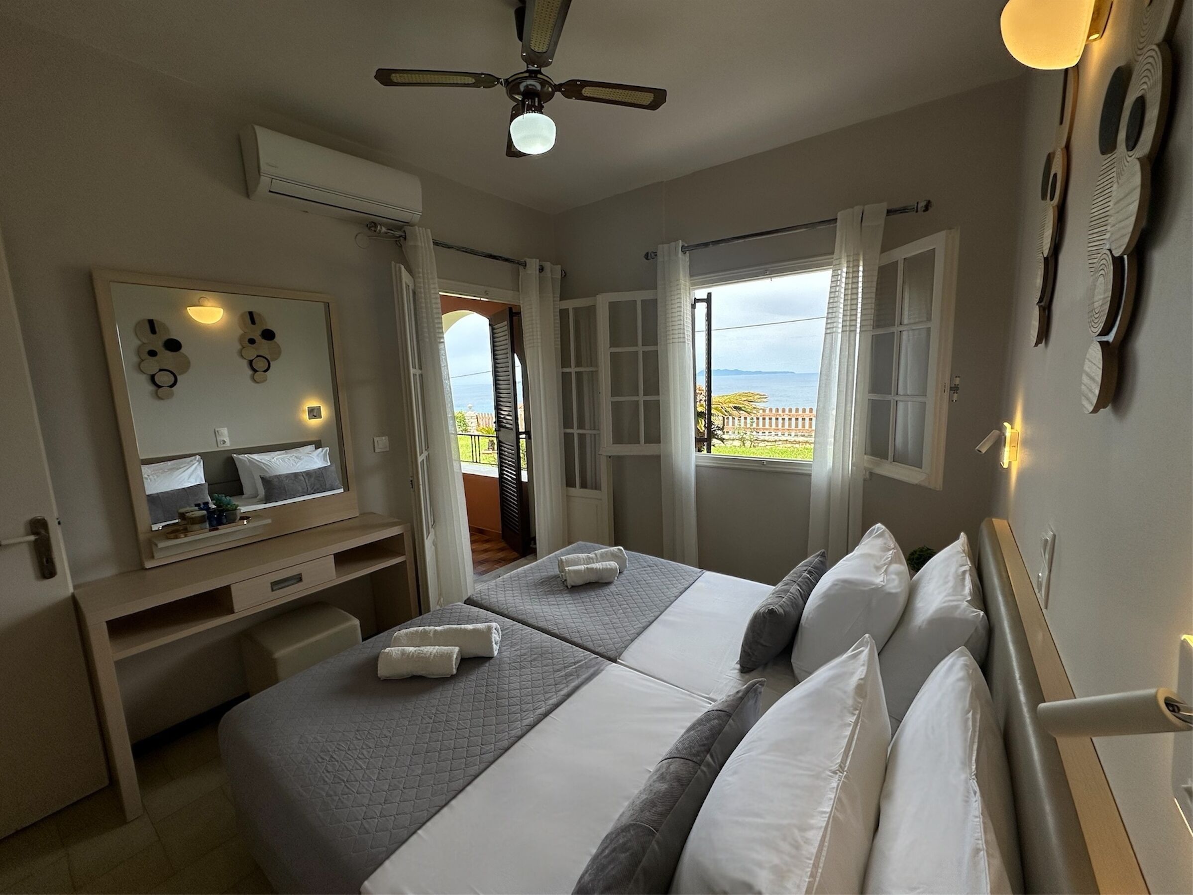 Ein Schlafzimmer mit zwei Betten, einem großen Spiegel und einem Deckenventilator.
