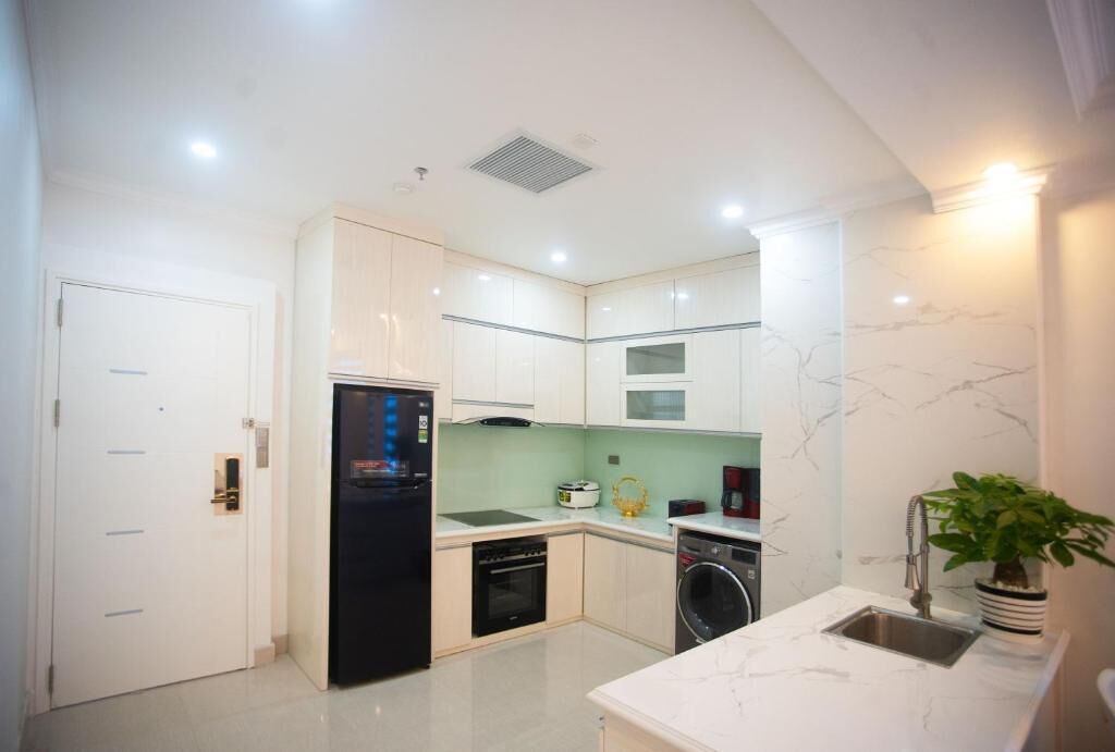 A modern kitchen with white cabinets, a black refrigerator, a microwave, a sink, and a dishwasher.