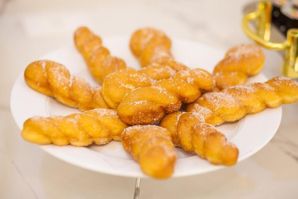 A plate of twisted doughnuts dusted with sugar.