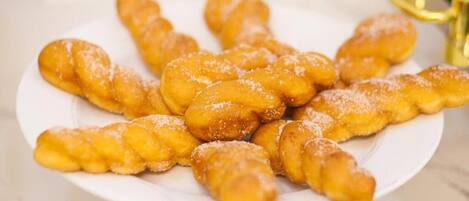 A plate of twisted doughnuts dusted with sugar.