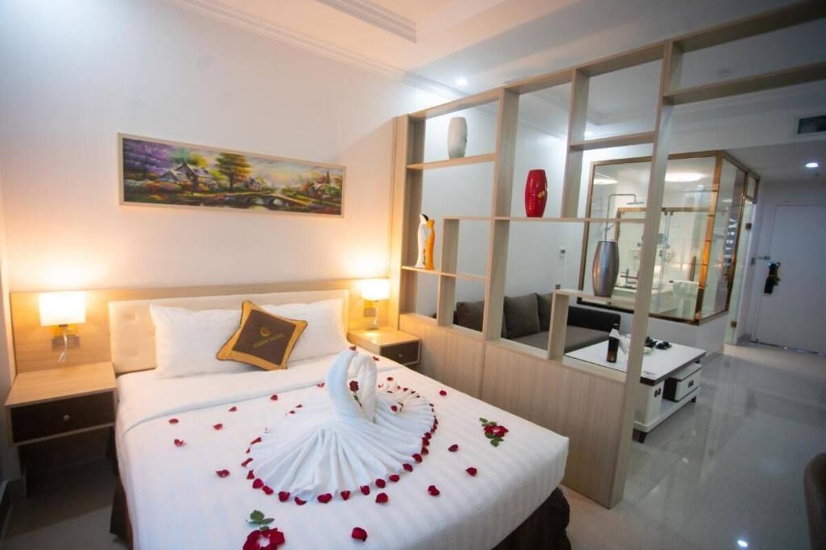 Una habitación de hotel con una cama bien hecha, un cuadro en la pared y una división de madera con estantes.